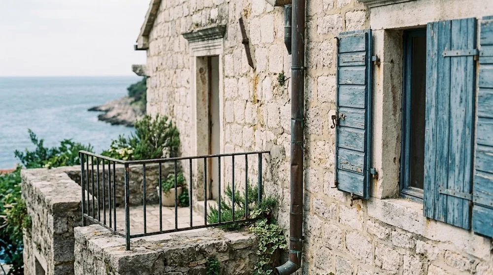 Stone terrace with weathered railing, timber shutters and drainage